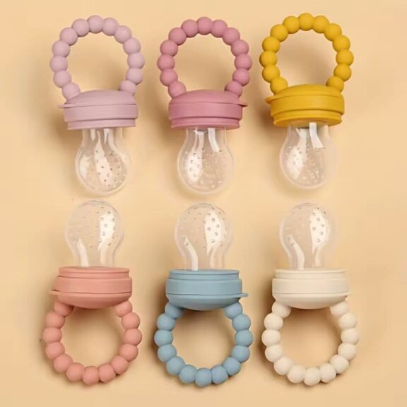Ensemble de six tétines grignoteuses pour bébé aux poignées en perles colorées, disposées verticalement sur fond beige